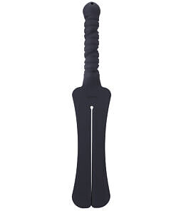 Tantus Trip 2 Tawse silicone paddle whip with dual 1.5-inch tongues lying on dark textured surface next to storage bag.