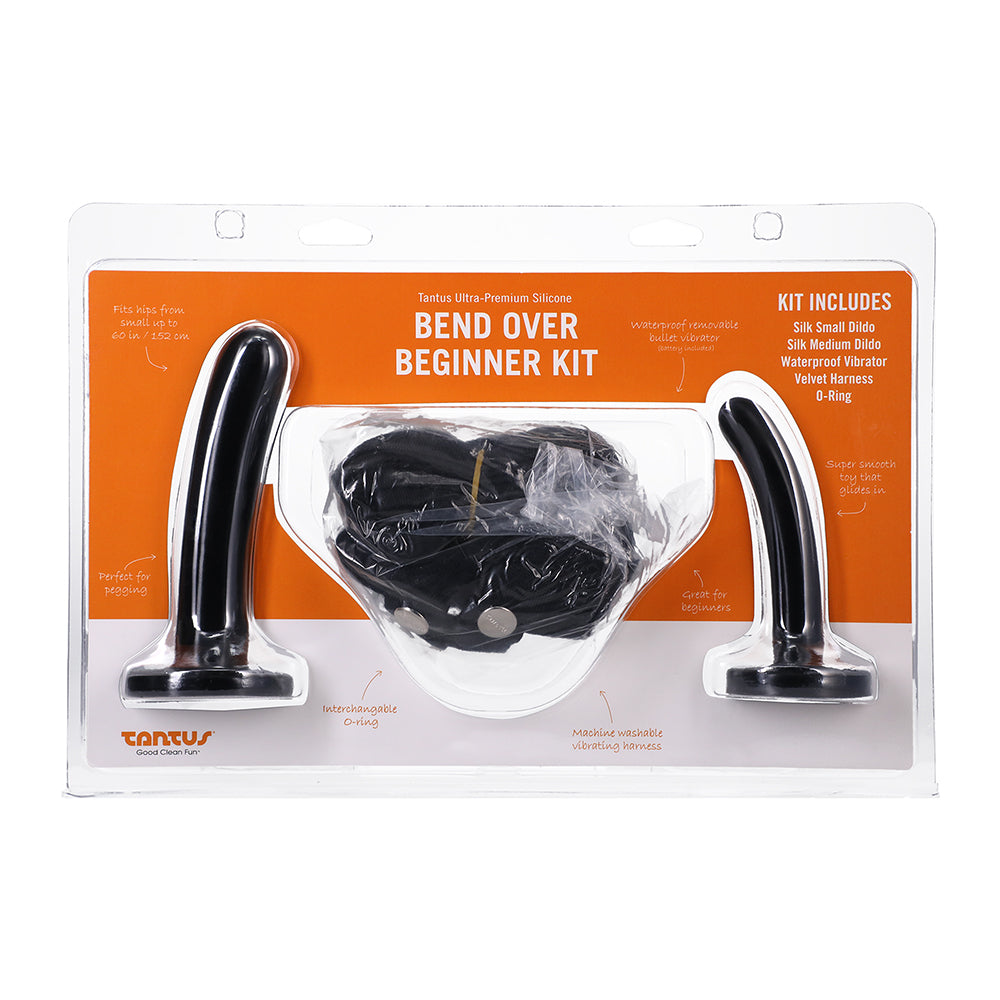 Tantus Bend Over Beginner Kit Onyx with two black silicone dildos and fabric harness laid flat on a dark background.