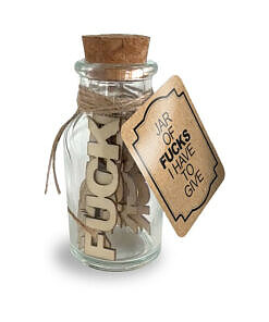 Jar Of Fucks I Have To Give clear glass jar with fifteen wooden tokens on desk surface next to coffee cup
