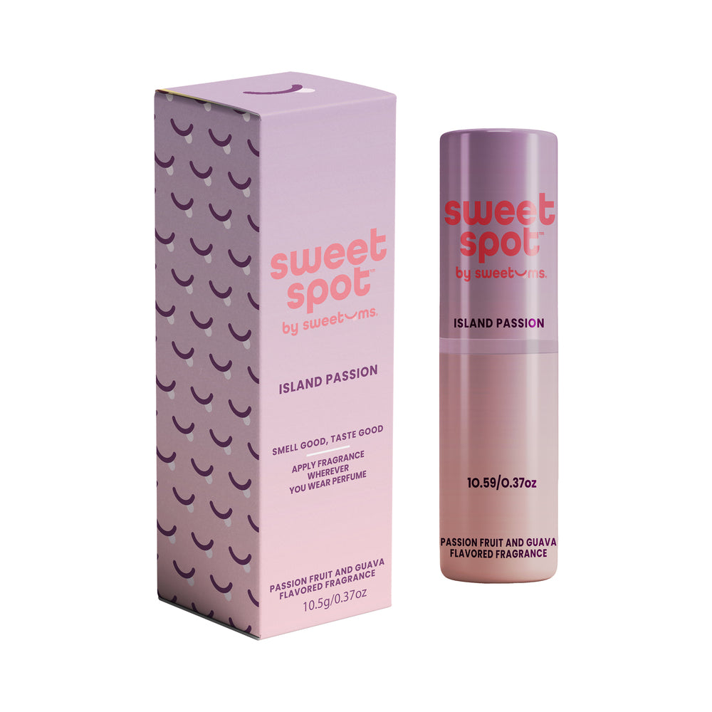 Sweetums Sweet Spot Flavored Fragrance Island Passion 2 fl oz spray bottle beside sliced mango and passionfruit on a bamboo backdrop.