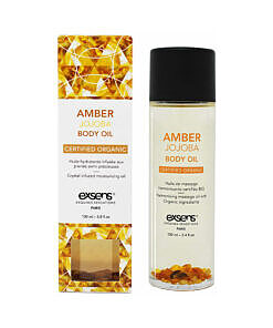 Exsens Amber Jojoba Body Oil 3.4 oz bottle on a spa table with soft floral accents and warm amber tones.