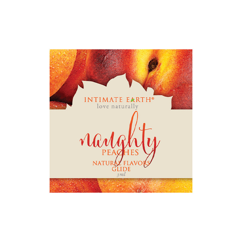 Intimate Earth Naughty Peach lubricant foil packet next to a ripe peach on a clean white surface.