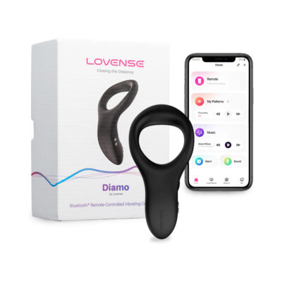 Lovense Diamo Bluetooth Vibrating Cockring in black silicone placed on a bed next to a smartphone showing the Lovense app.