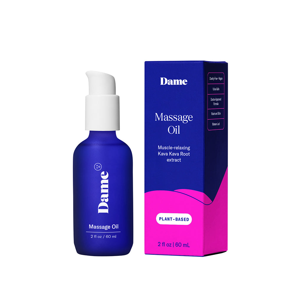 Dame Sex Oil Massage Oil 2 oz bottle beside a smooth stone and candle