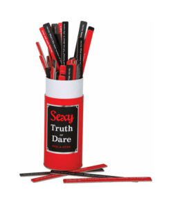 Sexy Truth or Dare Pick-A-Stick game box open on a bed with scattered double-sided sticks and soft candlelight.
