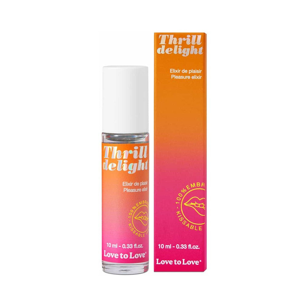 Love to Love Thrill Delight Pleasure Elixir 0.33 oz roll-on bottle on satin fabric beside a fresh coconut